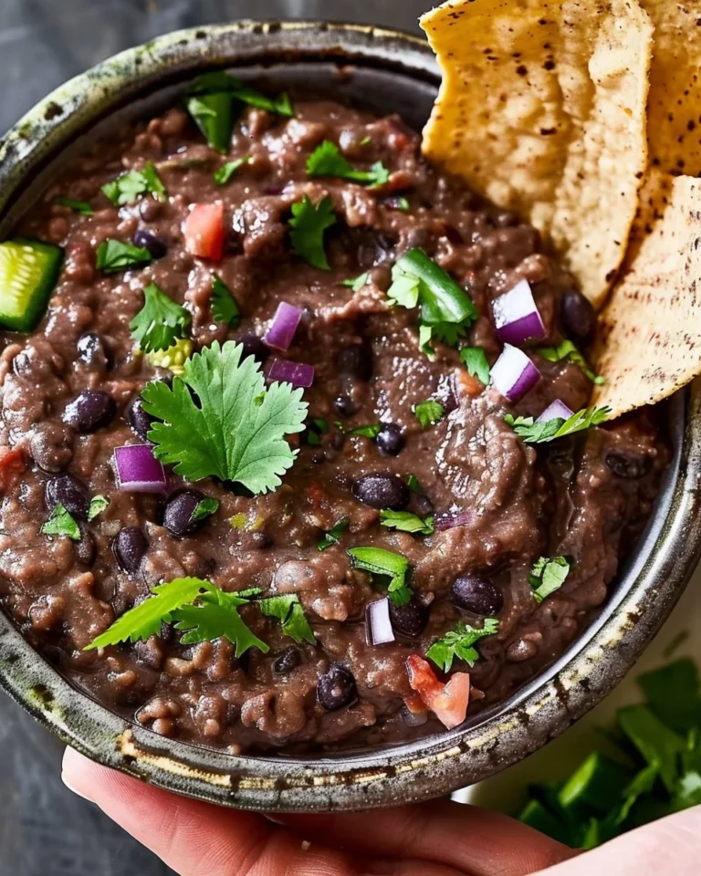 Easy 5-ingredient black bean dip in a bowl, garnished with herbs and served with chips.